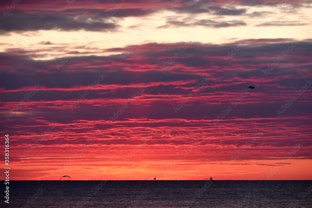 Colorful red sunset sunrise at sea. Water and sky. Minimalism in nature. Dark photo at dusk. Sea landscape. Colorful red sunset sunrise at sea. Water and sky. Minimalism in nature. Dark photo at dusk. Sea landscape.