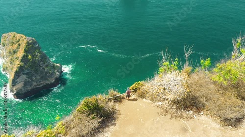 Aerial view traveler hiker on top of mountain cliff on background amazing nature landscape insland Bali, Indonesia. 4K View from above the ocean. Active lifestyle and Travel concept. photo