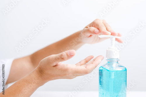 Close up Asian young woman applying press dispenser sanitizer alcohol gel pump to hand wash cleaning, hygiene prevention COVID-19 or coronavirus protection concept, isolated on white background