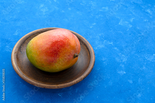 Appetizing ripe juicy Brazilian mango fruit from the tropics on a plate on a blue background with copy space. Exotic fresh fruits. vitamins and healthy nutrition healthy lifestyle