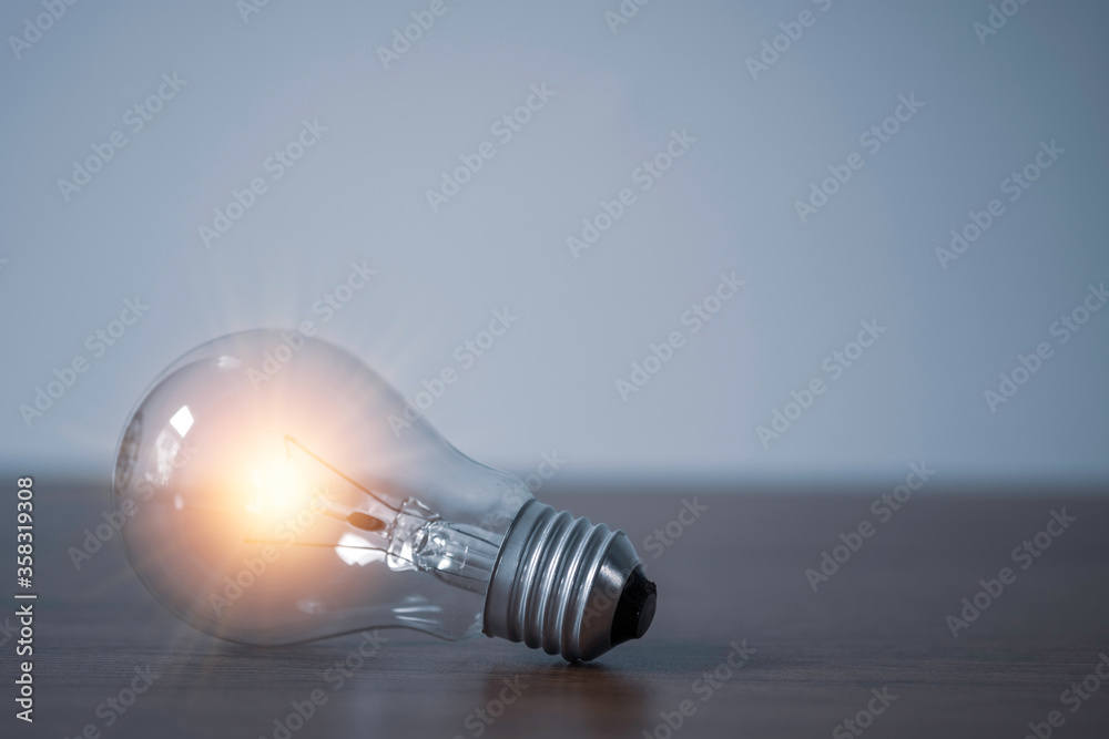 Closeup of lightbulb with orange glowing on the table. Creative idea concept. Closeup of lightbulb with orange glowing on the table. Creative idea concept.