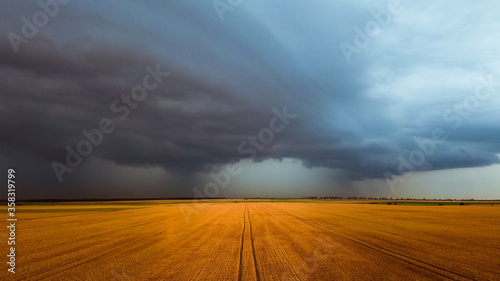 Storm and rainbow in the agricultural plain in summer time aerial photo