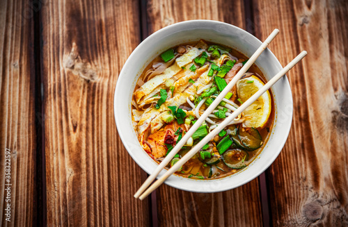 Spicy asian Korean kuksi soup in bowl on wooden table background