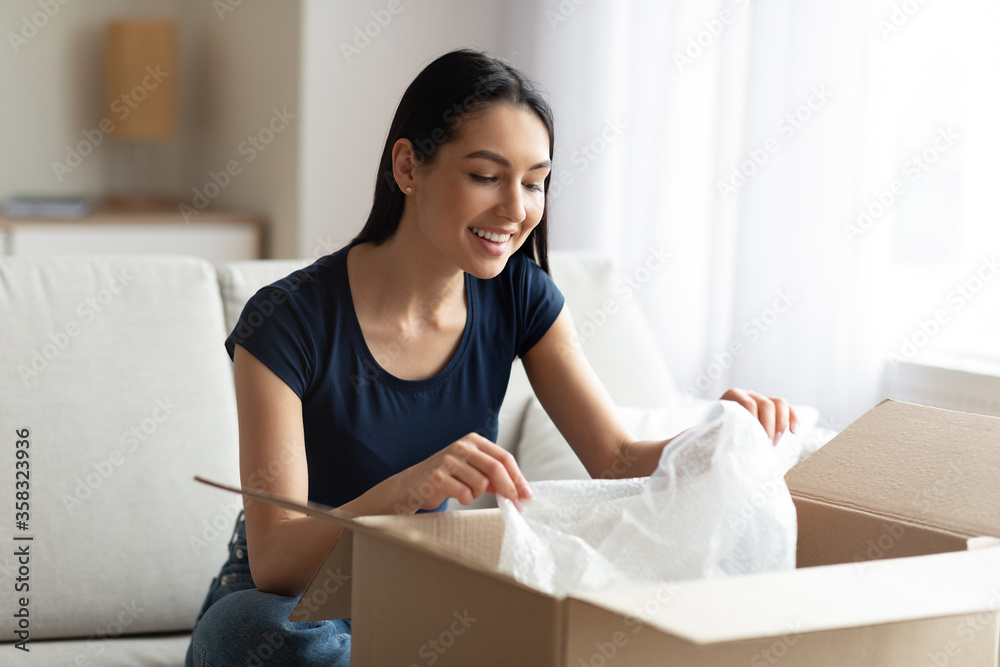 Happy Woman Unpacking Parcel Box Sitting On Sofa At Home Happy Woman Unpacking Parcel Box Sitting On Sofa At Home