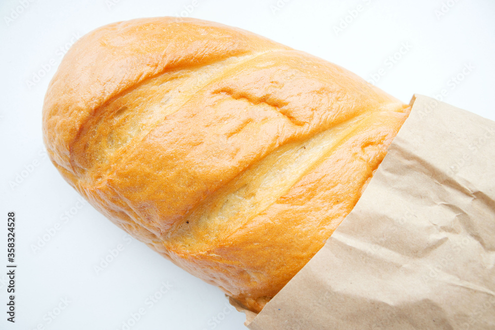 A loaf of fresh white bread, ciabatta with a crust, in a paper, craft ...