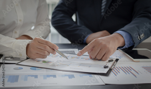 Asian business men and women are brainstorming and analyzing corporate financial graph data in the office.