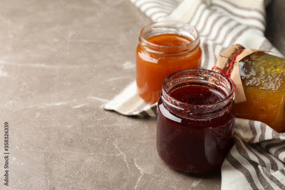 Napkin and glass jars with jam on gray background, space for text Napkin and glass jars with jam on gray background, space for text