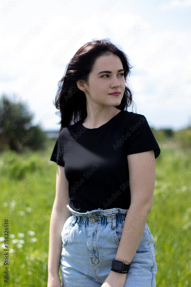 Charming young brunette woman in a black T-shirt and denim shorts. In the country, in the garden. High quality photo Charming young brunette woman in a black T-shirt and denim shorts. In the country, in the garden. High quality photo