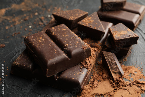 Tasty chocolate and powder on black background