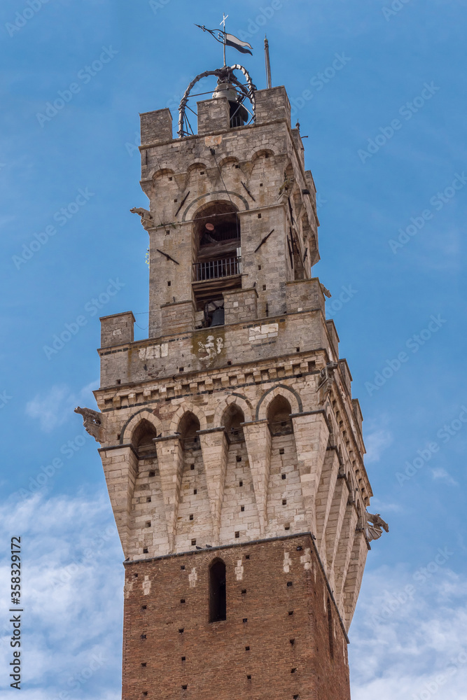 Detail of Mangia Tower and its tabernacle, the civic tower of the town hall of Siena in Piazza del campo. Tuscany, Italy