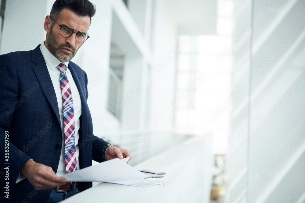 Portrait proud ceo in formal outfit checking documentation and quarter report from departure of corporation solving problems and creating optimal processes to improve work and increase income