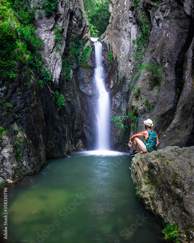 A water cascade in the forest with a man in front.
Une cascade d'eau dans la forêt avec un homme en face.
