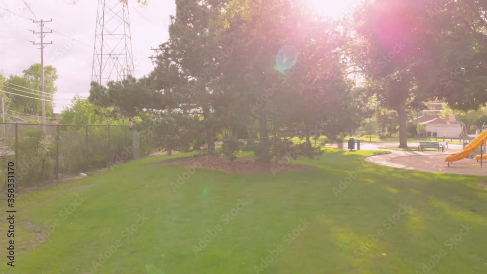 Sunlit Playground. A drone flies through the tree's at at suburban playground. Sunlit Playground. A drone flies through the tree's at at suburban playground.