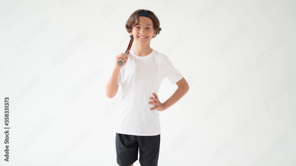 Little tennis player. Cheerful male teenager in white t-shirt holding tennis racket and looking at the camera with smile isolated on white background Little tennis player. Cheerful male teenager in white t-shirt holding tennis racket and looking at the camera with smile isolated on white background