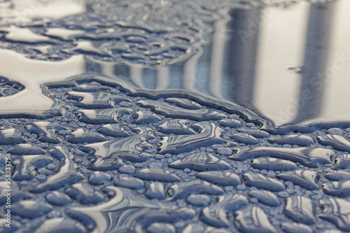 A building facade is reflected in early morning dew drops.