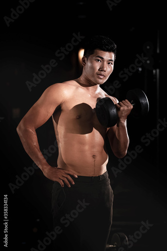 Handsome man raising dumbbell,doing exercise for buit muscle,fit and firm body,model posing
