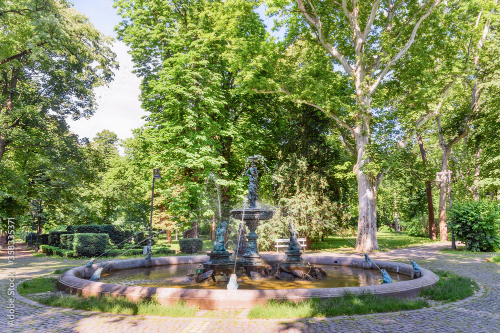 Vrsac, Serbia - June 04, 2020: Part of the fountain in the city park in Vrsac. Hiking trail through the alley in the city park.