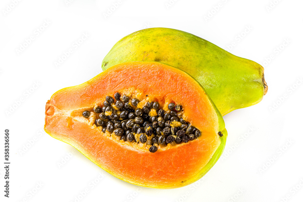 Raw juicy fresh papaya fruit isolate on a white background. Half and whole papaya on a white table Raw juicy fresh papaya fruit isolate on a white background. Half and whole papaya on a white table
