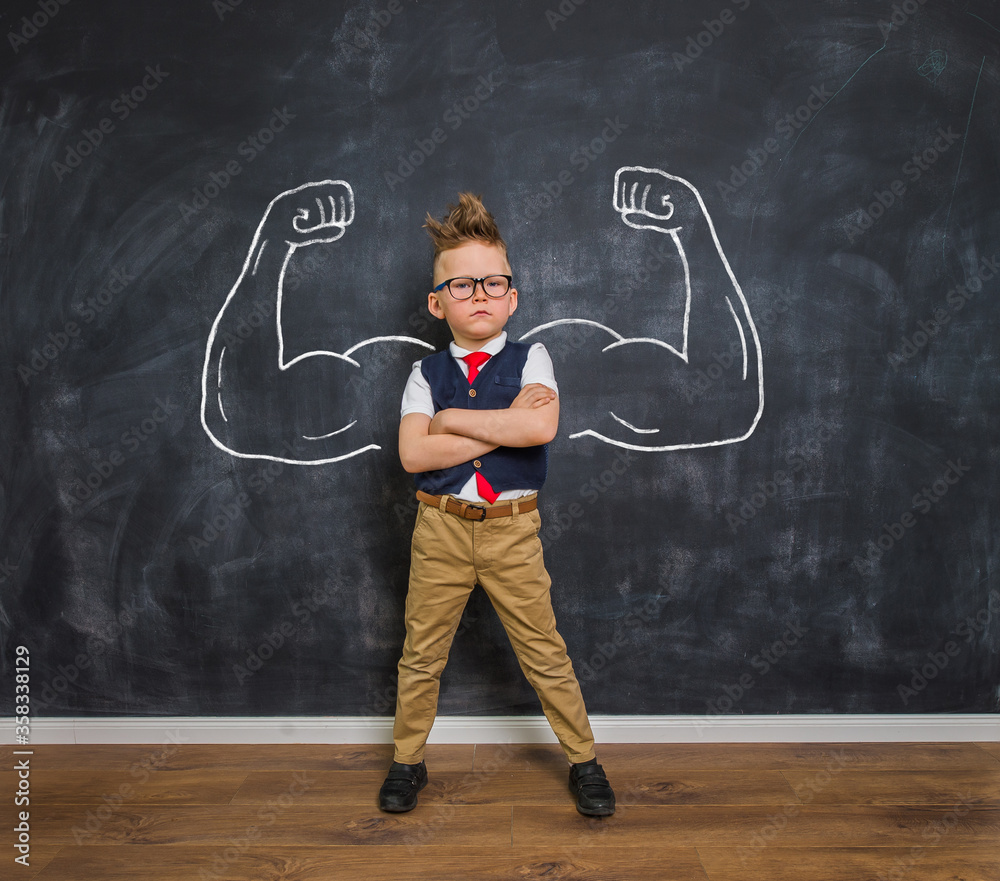 Portrait of smart kid boy with drawn muscles. Success, creative and innovation business concept