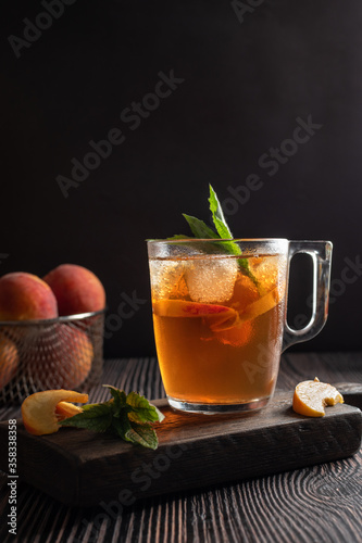 Ice tea with peach and mint on wooden table. Vertical orientation. Copy space. 