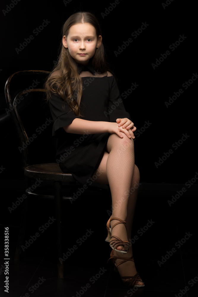 Portrait of a little girl sitting on an old Viennese chair, black background. Portrait of a little girl sitting on an old Viennese chair, black background.