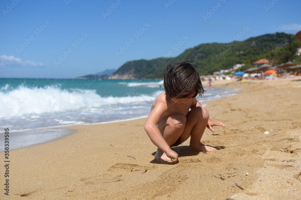 Child playing in sand on the beach. Cheerful boy play on send on summer holiday Child playing in sand on the beach. Cheerful boy play on send on summer holiday