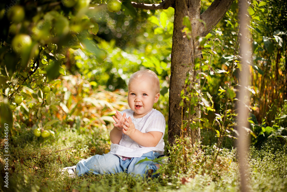 baby girl sitting on grass in garden under small Apple tree. gardening. baby girl sitting on grass in garden under small Apple tree. gardening.