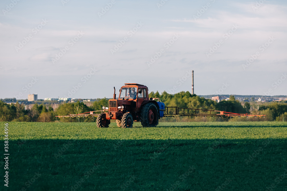 Obraz premium Tractor cultivating field at spring