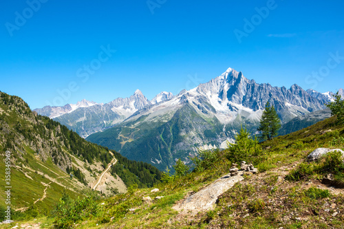 Alpine landscape with Mont Blanc mountains at summer from Plan Praz. Pyramid from stacked stones on a trail. France nature tourism background. Hiking, eco-planet concept.
