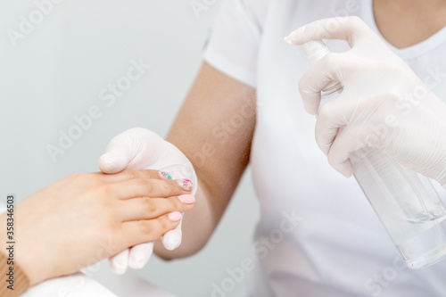 Manicurist is applying spray on client hand. Manicure disinfection with spray.