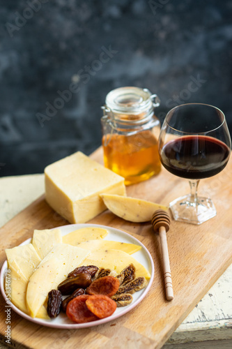 delicious cheese plate with aromatic wine, honey and dried fruits on a wooden board