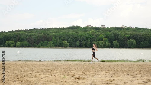 Pretty woman running on the sand beach near the water