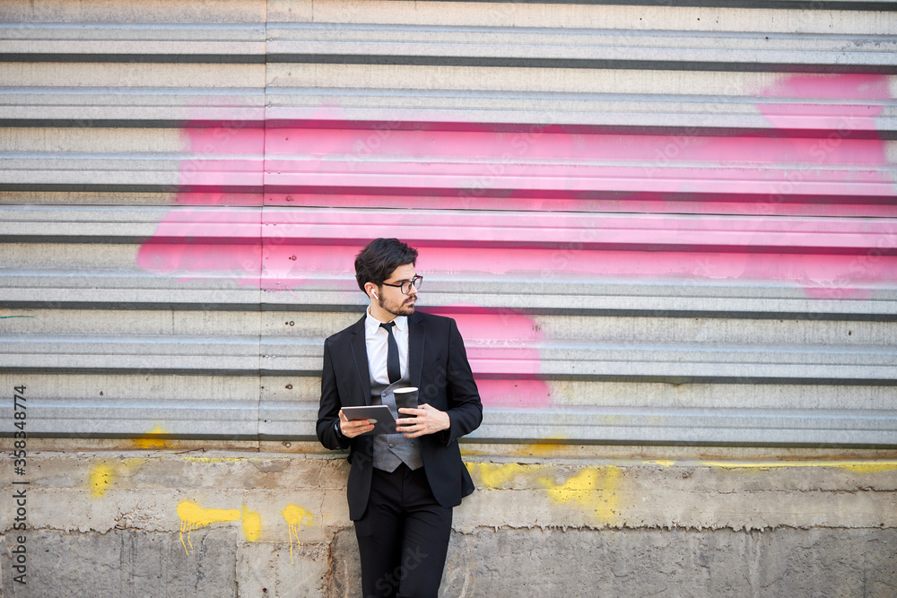 Young Businessman using a tablet pc outside wearing a classic suit