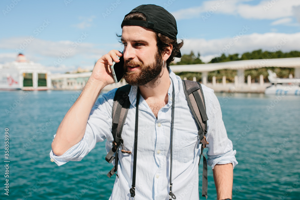 Obraz premium Man smiling while talking on the phone in front of the sea