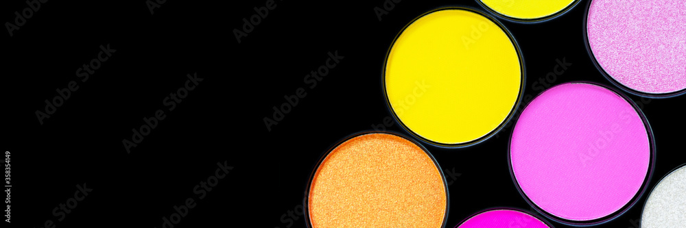 Bright multicolored neon eyeshadow palette. Beauty banner. Tool for makeup artist. Cosmetic products. Summer colorful yellow and pink eye shadows on black background isolated. Place for text. Closeup. - obrazy, fototapety, plakaty 