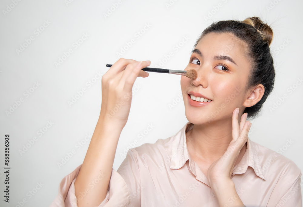 Asian women are using a make-up brush. Asian women are using a make-up brush.