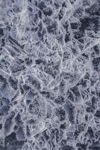 Transparent ice background. Close up of ice formation used as abstract background. Network of cracks in thick solid layer of ice of a frozen river.
