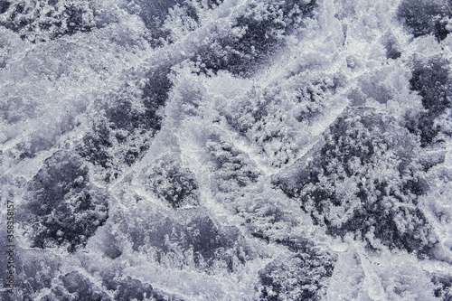 Transparent ice background. Close up of ice formation used as abstract background. Network of cracks in thick solid layer of ice of a frozen river.