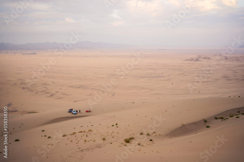 Stunning aerial image of sand dune desert with two SUVs and two peronas camping in tents