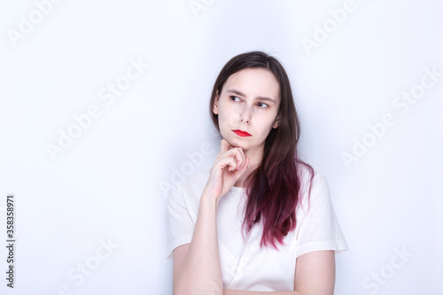 Young woman with red lipstick looks thoughtfully to side. Copy space