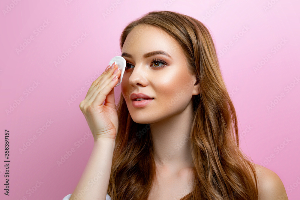 Portrait of a beautiful girl holding a sponge on a pink background