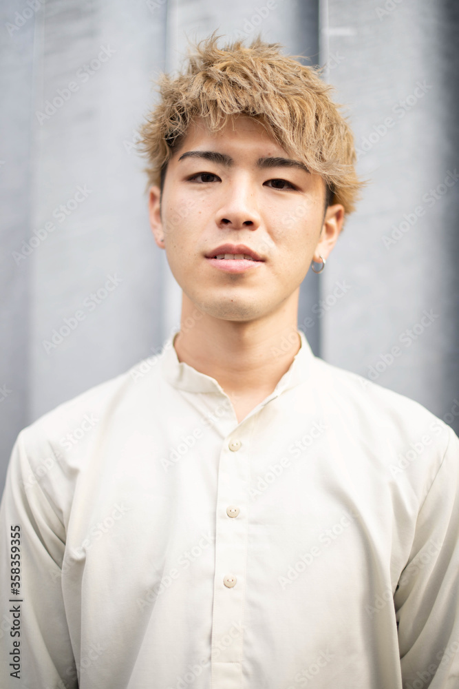 金髪の若い日本人青年男性がカメラ目線でこちらを見ている様子 Stock Foto Adobe Stock