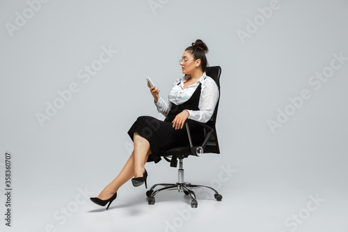 Paperwork. Young woman in office attire. Bodypositive female character, feminism, loving herself, beauty concept. Plus size businesswoman scrolling phone. Boss, beautiful girl. Inclusion, diversity.