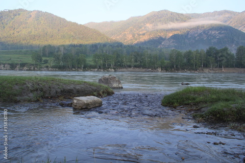 wide river flows on the background of the misty mountains
