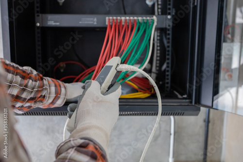 Young network administrator pluging in wires. Electrician engineer tests electrical installations and wires on relay protection system