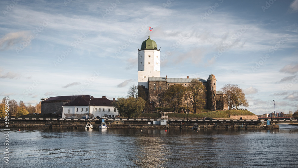 high old tower of St. Olav of the Vyborg castle on the island is reflected in the water of the Gulf of Finland on a sunny autumn day