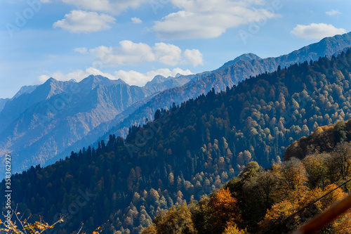 Sochi, Rosa hutor. The mountain view on a sunny automn day. Contrast colors of landscape, deep blue sky and bright utumnal leaves against high mountains peaks