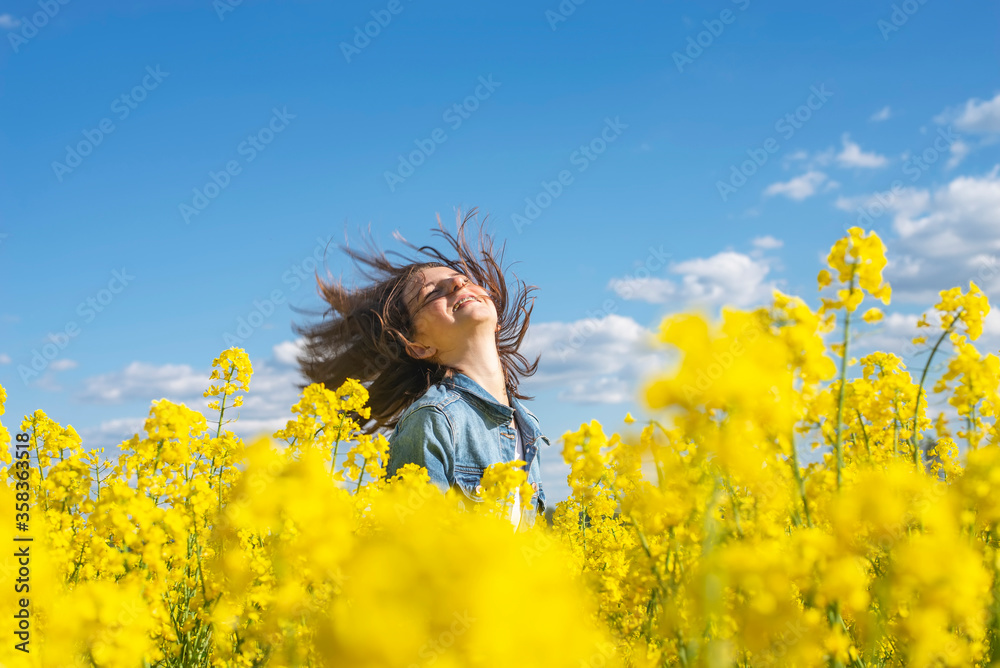 Happy teenage girl in rape field tossing her hair
