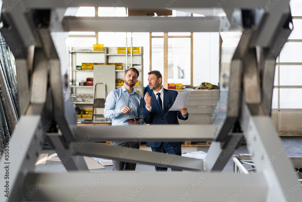 Two businessmen having a meeting in a factory Two businessmen having a meeting in a factory