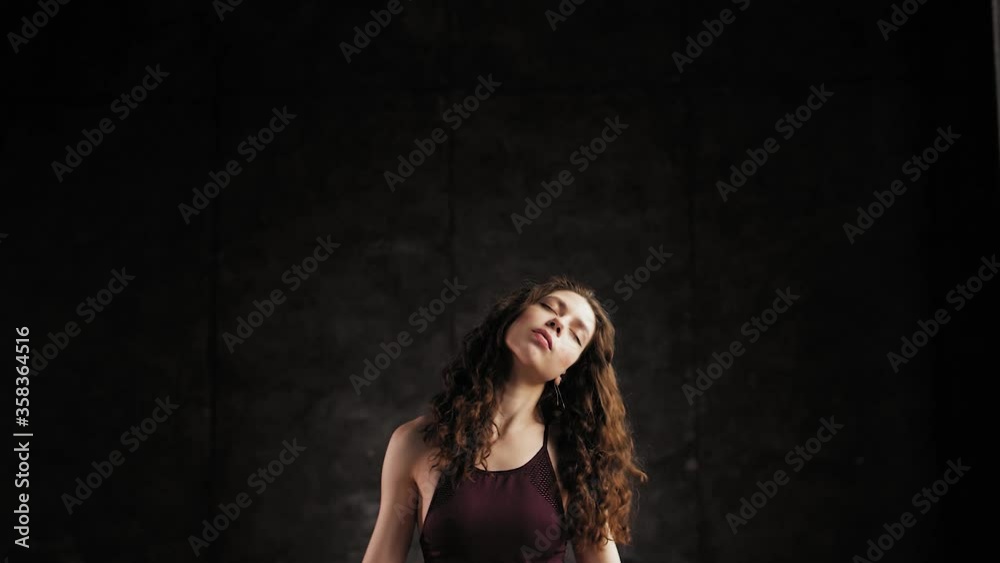 The girl shakes her head from side to side during meditation. Young girl in a dark room and meditation in the style of yoga. Slowmotion The girl shakes her head from side to side during meditation. Young girl in a dark room and meditation in the style of yoga. Slowmotion